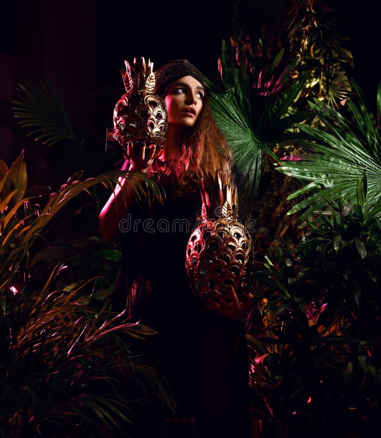 Belle femme de cheveux bouclés de mode posant dans la robe moderne dans la forêt tropicale de feuilles avec le grand fruit d'anan image libre de droits Belle femme de cheveux bouclés de mode posant dans la robe moderne dans la forêt tropicale de feuilles avec le grand fruit d'anan image libre de droits