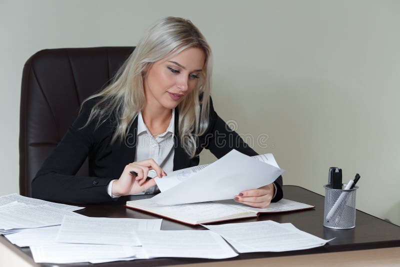 Belle femme de sourire d'affaires travaillant à son bureau avec des documents images stock Belle femme de sourire d'affaires travaillant à son bureau avec des documents images stock