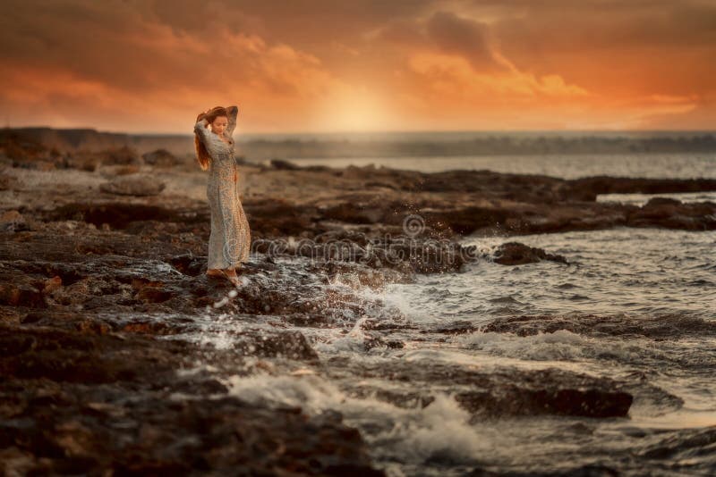 Belle femme en bord de la mer de roches au lever de soleil images libres de droits Belle femme en bord de la mer de roches au lever de soleil images libres de droits