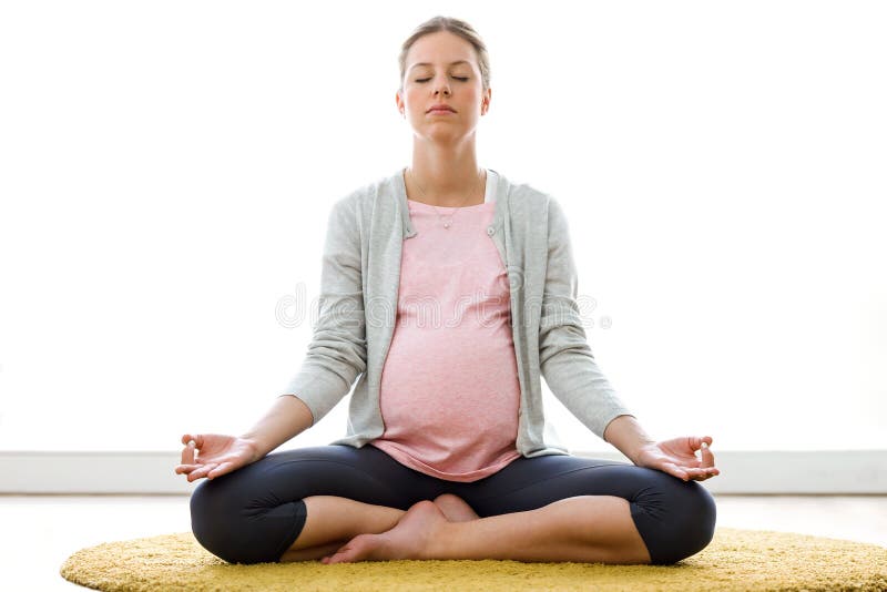 Belle femme enceinte faisant le yoga, se reposant en position de lotus à la maison photographie stock Belle femme enceinte faisant le yoga, se reposant en position de lotus à la maison photographie stock