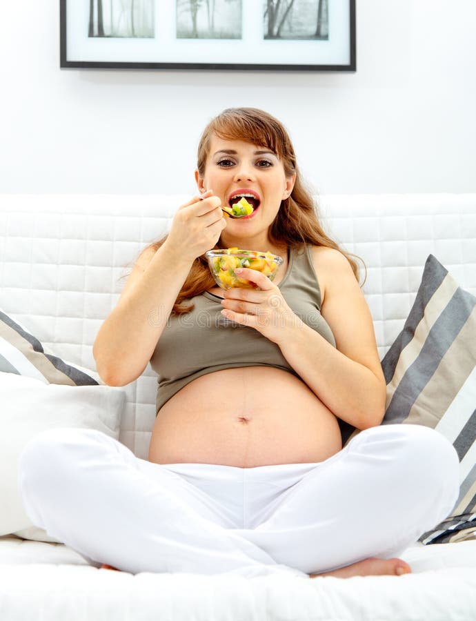 Belle femme enceinte heureuse mangeant de la salade de fruits images stock Belle femme enceinte heureuse mangeant de la salade de fruits images stock