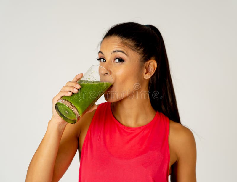 Belle femme heureuse de sport d'ajustement souriant et buvant le smoothie sain de légume frais image stock Belle femme heureuse de sport d'ajustement souriant et buvant le smoothie sain de légume frais image stock