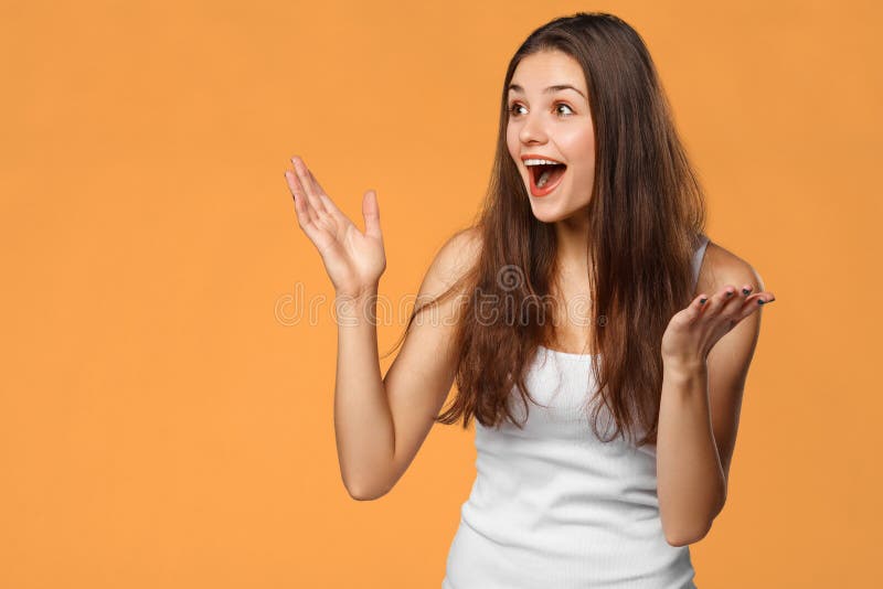 Belle femme heureuse étonnée regardant en longueur dans l'excitation, d'isolement sur le fond orange photos libres de droits