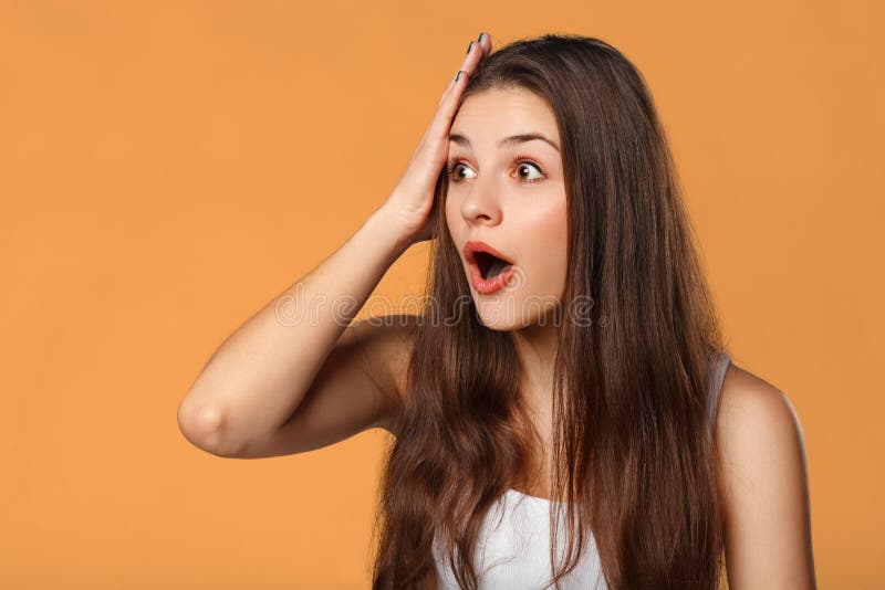 Belle femme heureuse étonnée regardant en longueur dans l'excitation D'isolement sur le fond orange photographie stock libre de droits Belle femme heureuse étonnée regardant en longueur dans l'excitation D'isolement sur le fond orange photographie stock libre de droits