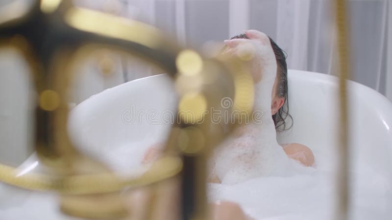 Belle femme relaxant dans le bain à bulles qui se retrouvent aussi bien dans la baignoire Gisant gay et décontracté dans la baign