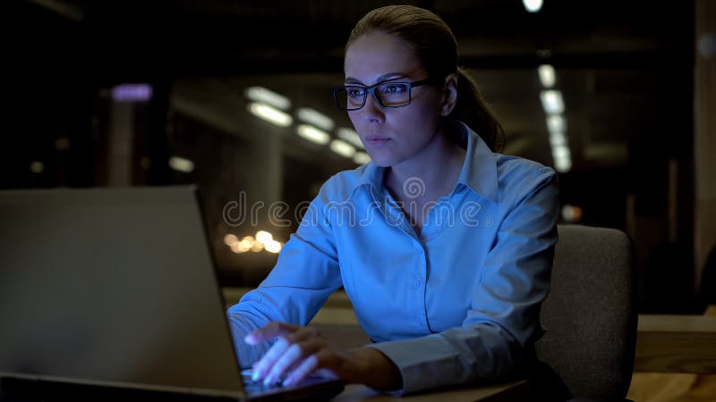 Belle femme travaillant sur l'ordinateur portable de fin de nuit dans le bureau, employée consciencieuse images libres de droits Belle femme travaillant sur l'ordinateur portable de fin de nuit dans le bureau, employée consciencieuse images libres de droits