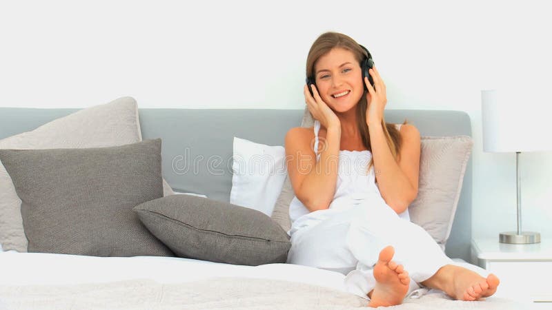 Belle femme écoutant la musique dans son lit