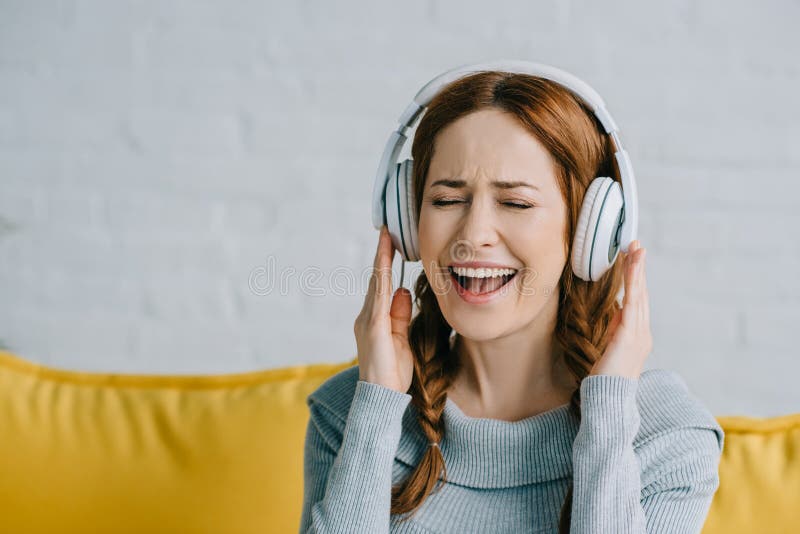 Beautiful woman listening to music and singing in living room. Beautiful woman listening to music and singing in living room