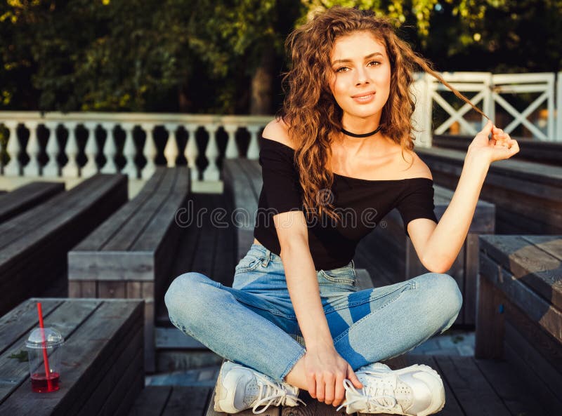 Belle fille aux cheveux longs s'asseyant en parc une soirée d'été Habillé dans un dessus noir et des jeans Belle source photo libre de droits Belle fille aux cheveux longs s'asseyant en parc une soirée d'été Habillé dans un dessus noir et des jeans Belle source photo libre de droits
