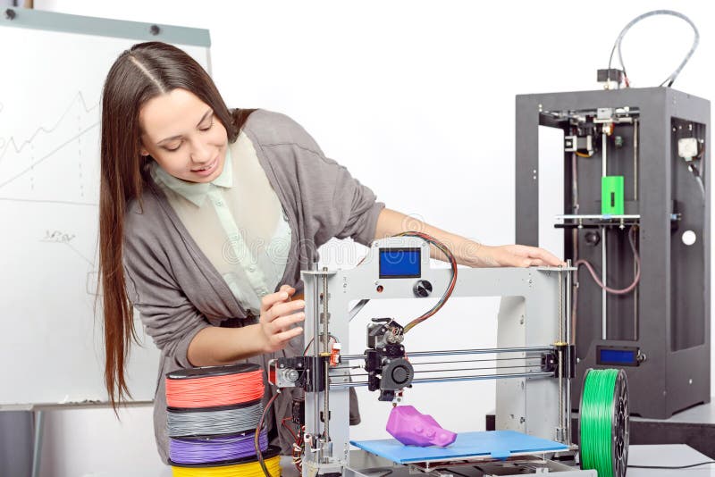 Beautiful young brunette student with long hair watching the process of 3d printing in a laboratory. Beautiful young brunette student with long hair watching the process of 3d printing in a laboratory