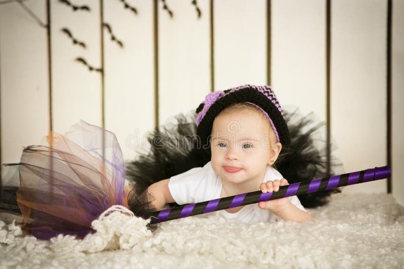 Belle fille avec la trisomie 21 dans un costume de la sorcière avec un balai photo stock Belle fille avec la trisomie 21 dans un costume de la sorcière avec un balai photo stock