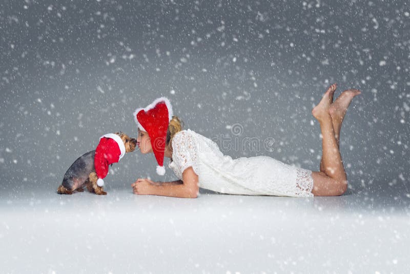 Belle fille avec le chien de yorkie dans le chapeau de Santa image stock Belle fille avec le chien de yorkie dans le chapeau de Santa image stock