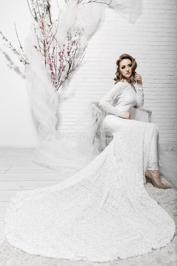 Belle fille avec les cheveux blonds dans une salle lumineuse se reposant sur le divan Jeune mari? e dans une belle longue robe seu photo libre de droits