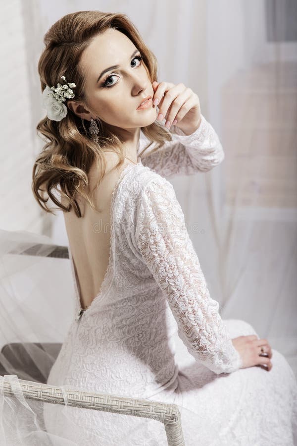 Belle fille avec les cheveux blonds dans une salle lumineuse se reposant sur le divan Jeune mari? e dans une belle longue robe seu image libre de droits