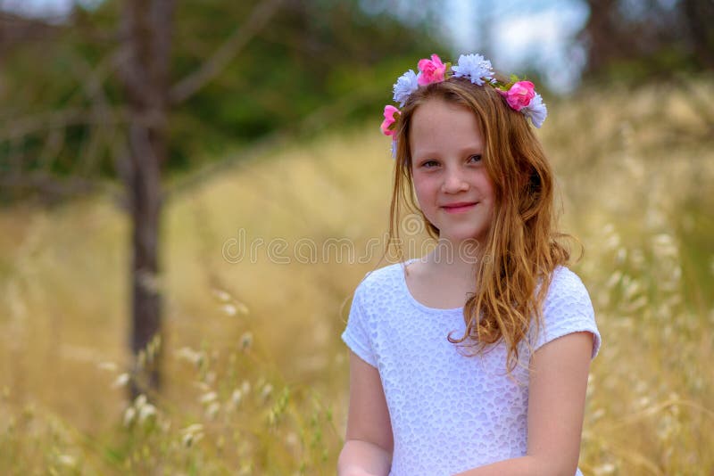 Belle fille avec une guirlande sur sa tête dans un domaine de blé images stock Belle fille avec une guirlande sur sa tête dans un domaine de blé images stock