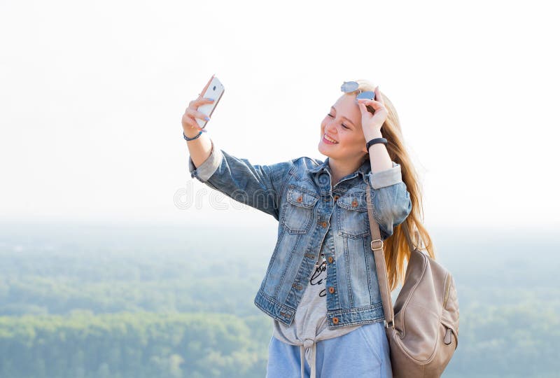 Belle fille blonde heureuse prenant des selfies dehors en parc photos libres de droits Belle fille blonde heureuse prenant des selfies dehors en parc photos libres de droits
