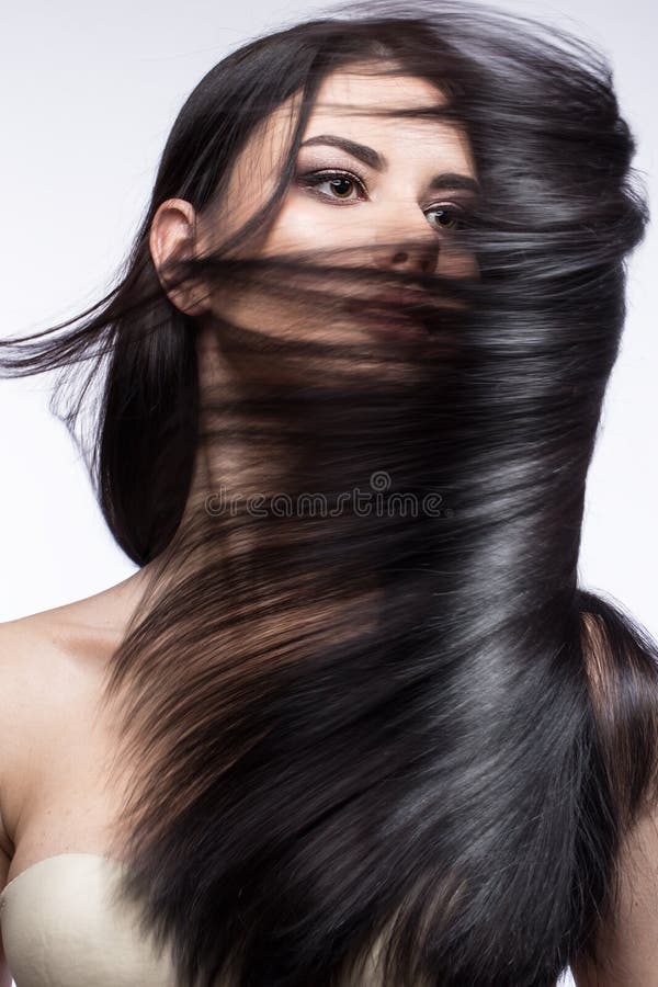 Belle fille de brune dans le mouvement avec des cheveux parfaitement lisses, et maquillage classique Visage de beauté images stock Belle fille de brune dans le mouvement avec des cheveux parfaitement lisses, et maquillage classique Visage de beauté images stock