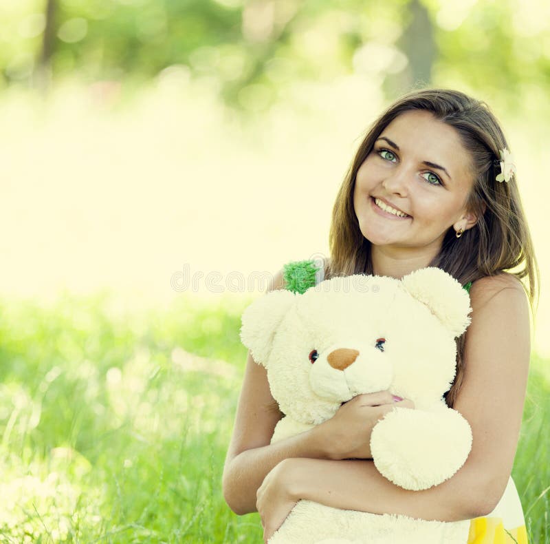 Belle fille de l'adolescence avec l'ours de nounours en stationnement à l'herbe verte. images libres de droits Belle fille de l'adolescence avec l'ours de nounours en stationnement à l'herbe verte. images libres de droits