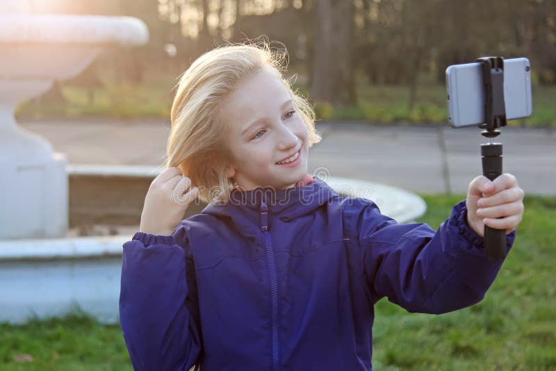 Belle fille de la préadolescence de sourire 9-11 ans prenant un selfie dehors Enfant prenant un autoportrait avec le téléphone po photos stock