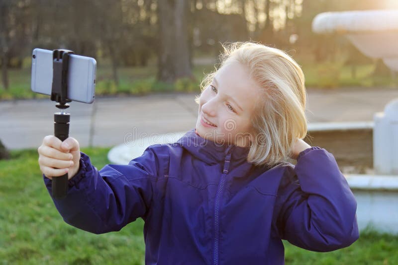 Belle fille de la préadolescence de sourire prenant un selfie dehors Enfant prenant un autoportrait avec le téléphone portable photo stock