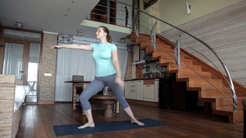 Belle fille de sports occupée dans la forme physique à la maison, s'étendant banque de vidéos