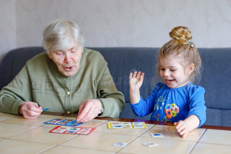 Belle petite fille et grand grand-mère en train de jouer ensemble images loto cartes de table jeu à la maison. enfant mignon et