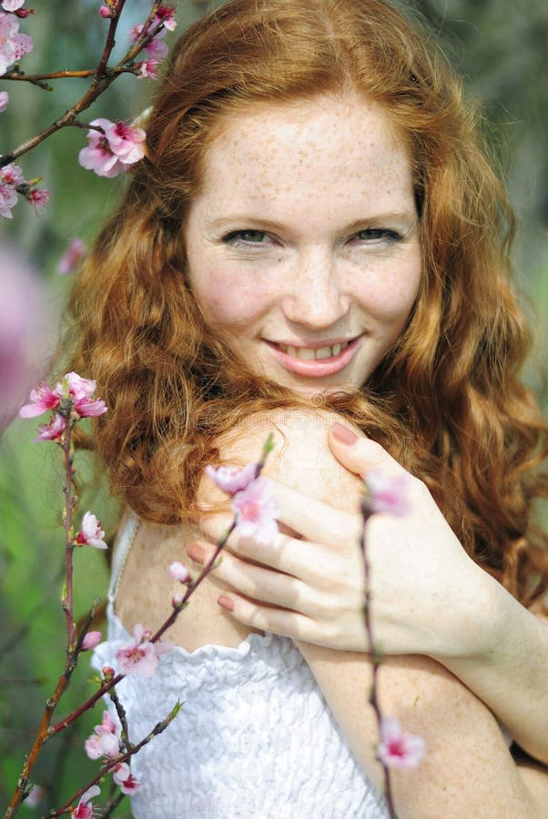 Belle fille rousse parmi les arbres fleurissants photographie stock libre de droits Belle fille rousse parmi les arbres fleurissants photographie stock libre de droits
