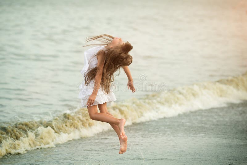 Belle fille sautant par les vagues photographie stock libre de droits Belle fille sautant par les vagues photographie stock libre de droits