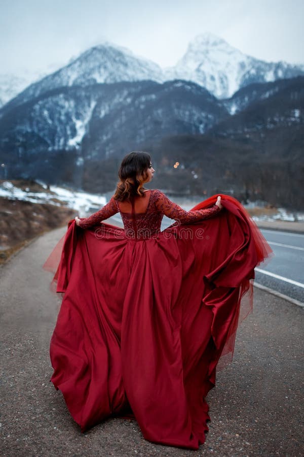Belle fille sexy élégante dans la grande robe fraîche rouge sur la route, en montagnes image libre de droits Belle fille sexy élégante dans la grande robe fraîche rouge sur la route, en montagnes image libre de droits