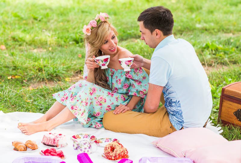 Belle giovani coppie che hanno picnic in campagna Famiglia felice esterna Uomo e donna sorridenti che si rilassano nel parco fotografia stock Belle giovani coppie che hanno picnic in campagna Famiglia felice esterna Uomo e donna sorridenti che si rilassano nel parco fotografia stock