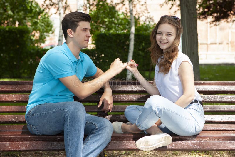 Belle giovani coppie che si siedono su un banco nel parco fotografia stock libera da diritti Belle giovani coppie che si siedono su un banco nel parco fotografia stock libera da diritti