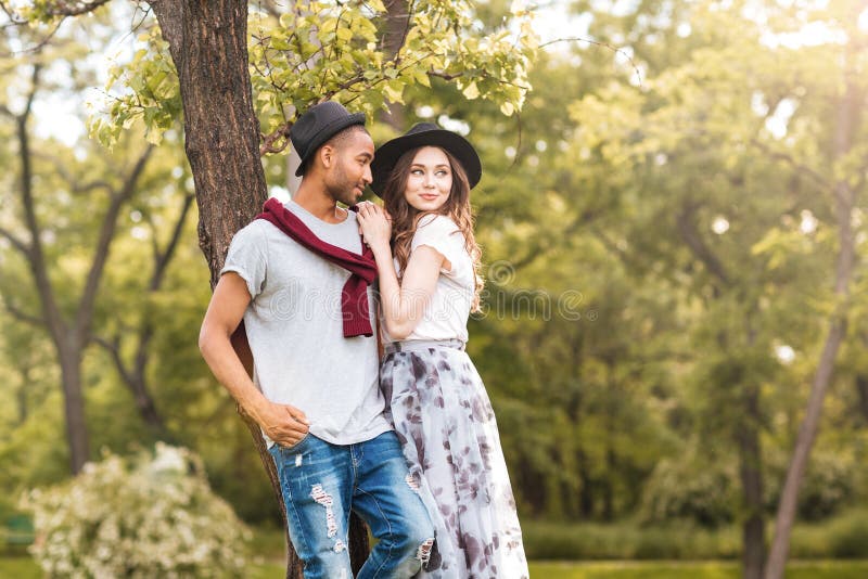 Belle giovani coppie che stanno insieme nel parco immagine stock Belle giovani coppie che stanno insieme nel parco immagine stock