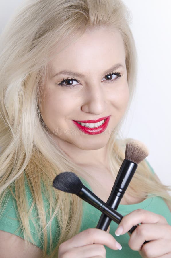 Belle giovani spazzole bionde sensuali di trucco della tenuta attraversate immagini stock libere da diritti Belle giovani spazzole bionde sensuali di trucco della tenuta attraversate immagini stock libere da diritti