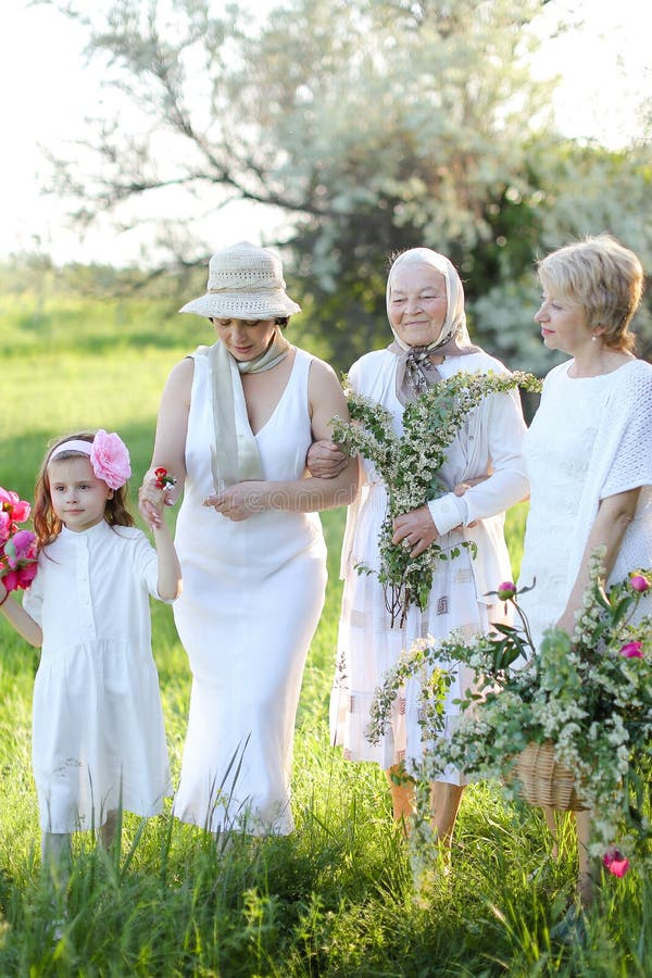Belle grand-mère en robe blanche avec filles et petite-fille dehors. photos libres de droits