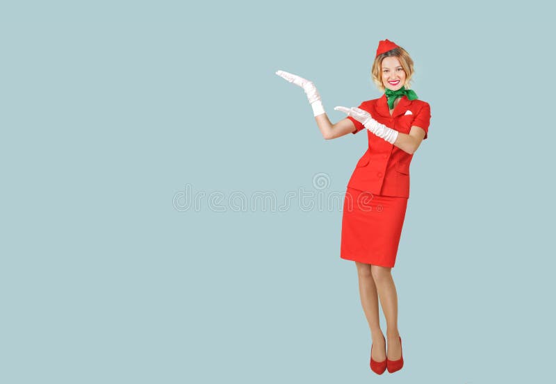 Belle hôtesse portant dans l'uniforme rouge sur le fond gris photo stock Belle hôtesse portant dans l'uniforme rouge sur le fond gris photo stock