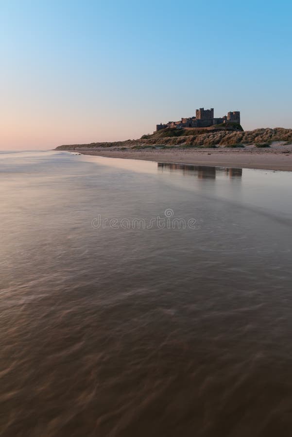 Stunning landscape image of Bamburgh Castle on Northumberland coast at sunrise with vibrant colors. Stunning landscape image of Bamburgh Castle on Northumberland coast at sunrise with vibrant colors