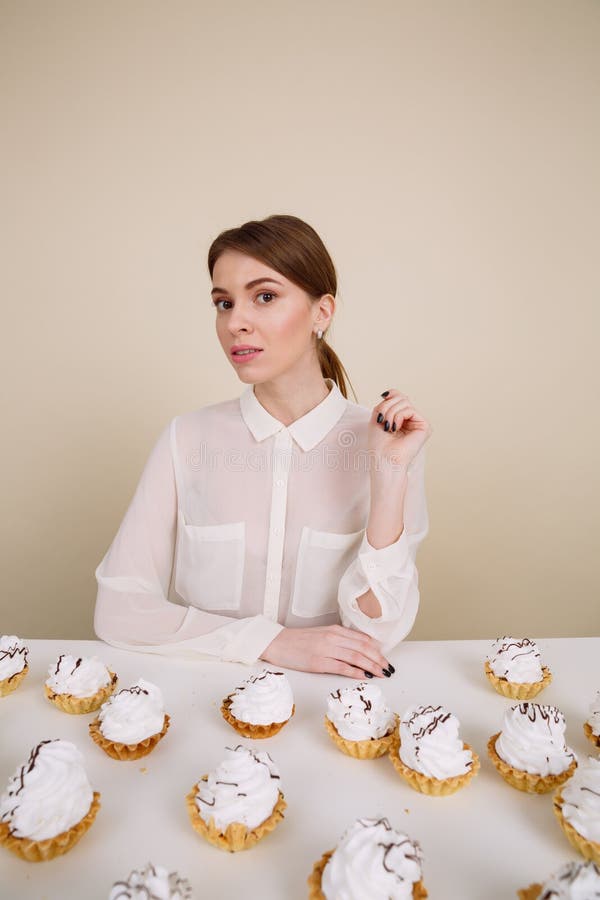 Belle jeune dame posant tout en se reposant près du petit gâteau image stock