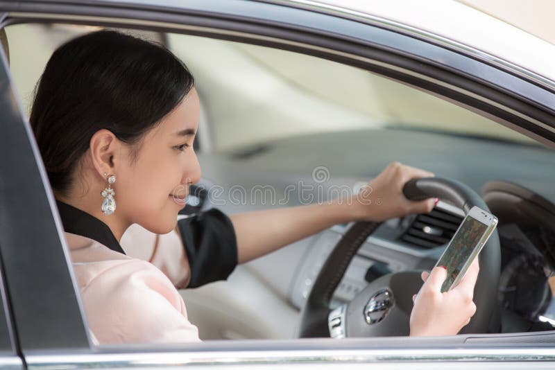 Belle jeune femme asiatique employant la carte dans le mobile dans une voiture image libre de droits Belle jeune femme asiatique employant la carte dans le mobile dans une voiture image libre de droits