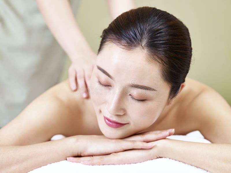 Belle jeune femme asiatique recevant le massage dans le salon de station thermale photo libre de droits Belle jeune femme asiatique recevant le massage dans le salon de station thermale photo libre de droits
