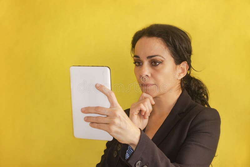 Belle jeune femme d'affaires, avec le tresse, veste noire, d'isolement sur un fond, regardant son comprimé photo stock Belle jeune femme d'affaires, avec le tresse, veste noire, d'isolement sur un fond, regardant son comprimé photo stock