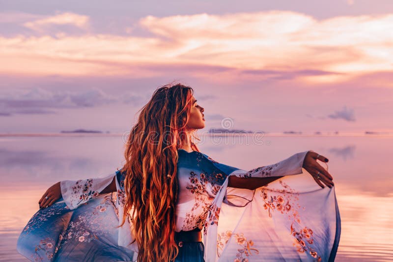 Belle jeune femme dans la robe élégante sur la plage au coucher du soleil photo libre de droits