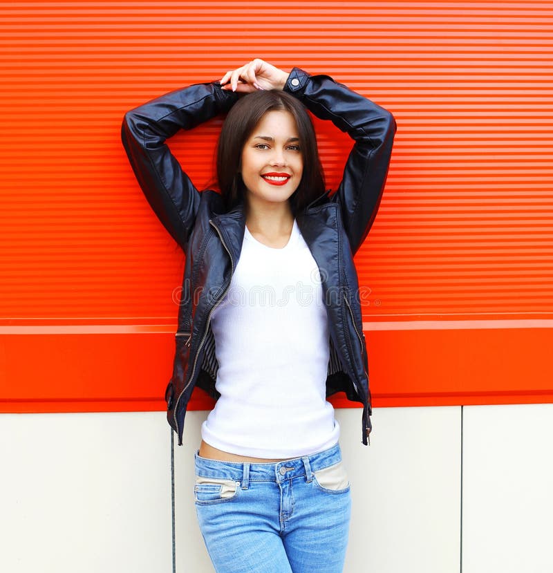 Belle jeune femme de sourire de brune de portrait utilisant une veste en cuir et des jeans de noir de roche posant dans la ville photos libres de droits Belle jeune femme de sourire de brune de portrait utilisant une veste en cuir et des jeans de noir de roche posant dans la ville photos libres de droits