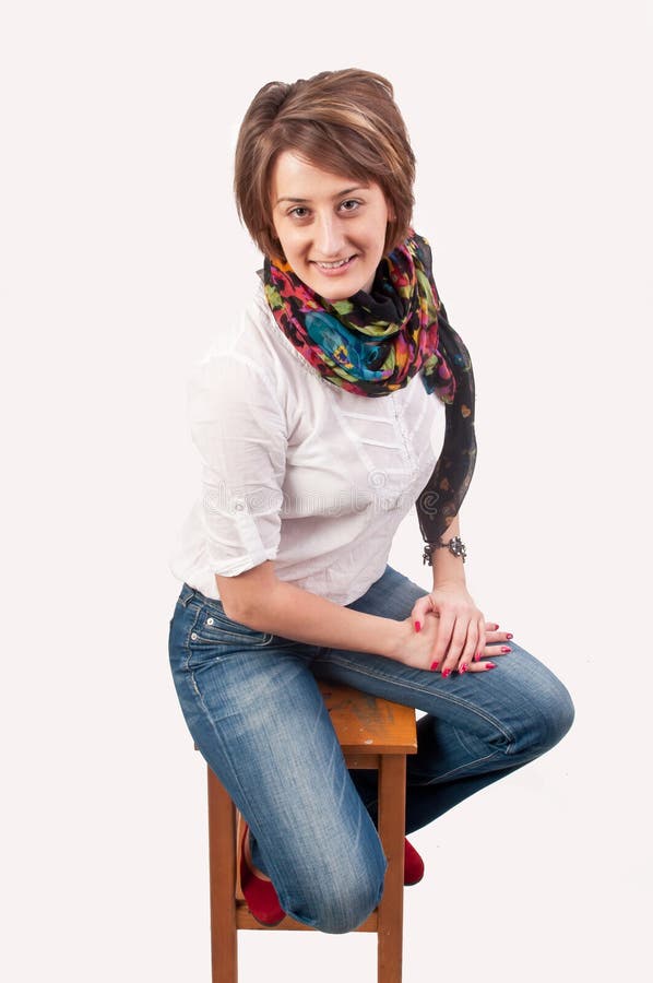 Belle jeune femme de sourire s'asseyant sur une chaise images libres de droits Belle jeune femme de sourire s'asseyant sur une chaise images libres de droits