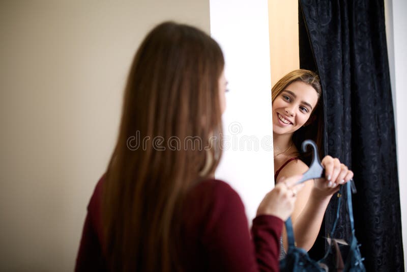 Belle jeune femme demandant une opinion d'amis dans la cabine d'essayage du magasin de lingerie La femelle essaye le soutien-gorg photographie stock libre de droits Belle jeune femme demandant une opinion d'amis dans la cabine d'essayage du magasin de lingerie La femelle essaye le soutien-gorg photographie stock libre de droits