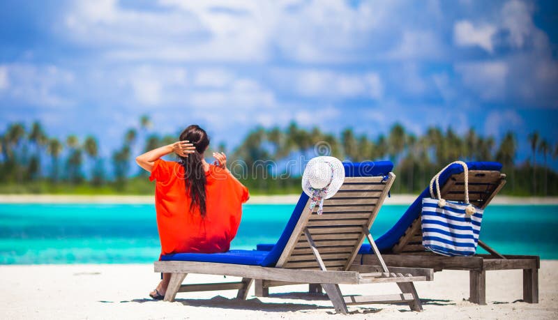 Belle jeune femme détendant aux chaises de plage photographie stock libre de droits Belle jeune femme détendant aux chaises de plage photographie stock libre de droits