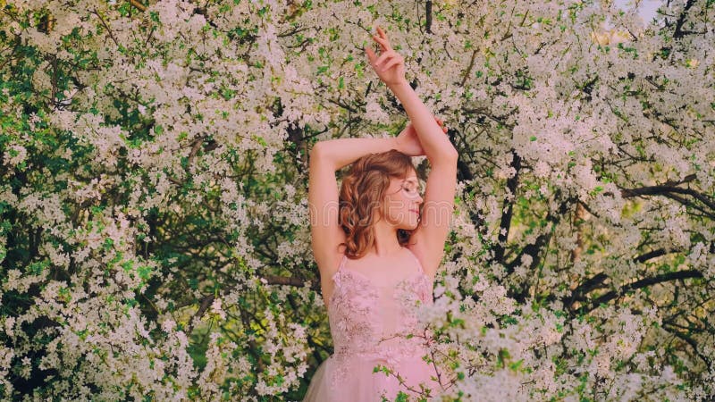 Belle jeune femme modèle de mode pose sur fond de ressort nature parc jardin fleuri arbre blanc fleurs banque de vidéos