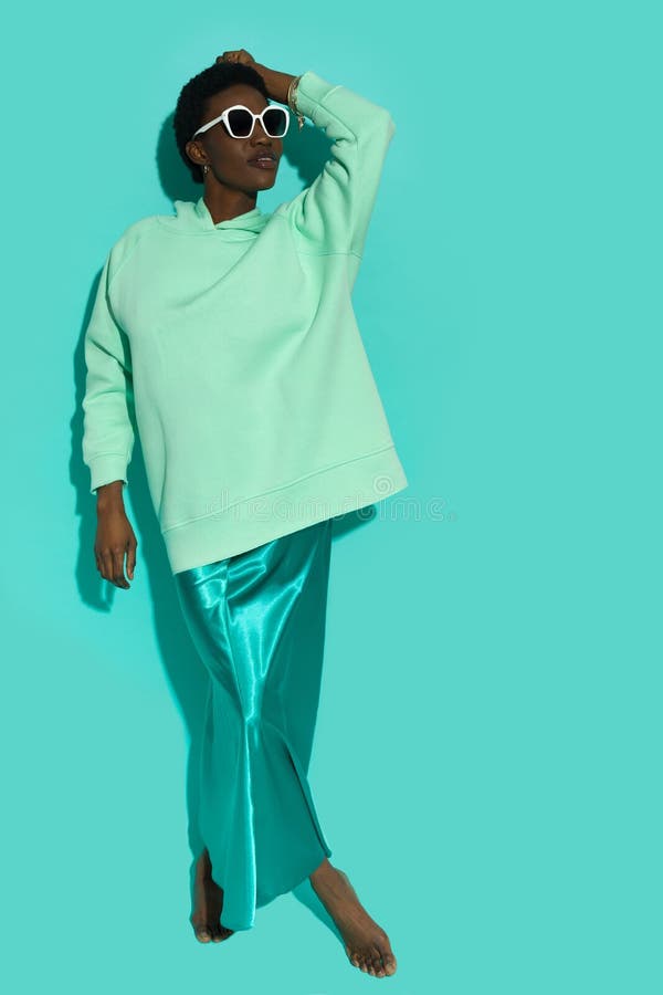Belle jeune femme noire en sweat surdimensionné et robe longue satinée et lunettes de soleil photos libres de droits