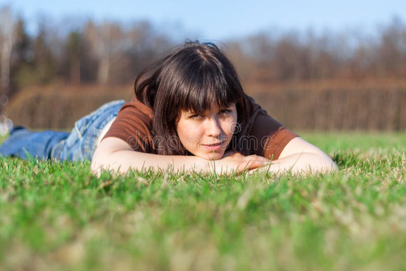 Belle jeune femme se trouvant sur un champ, herbe verte Dehors en photo stock Belle jeune femme se trouvant sur un champ, herbe verte Dehors en photo stock