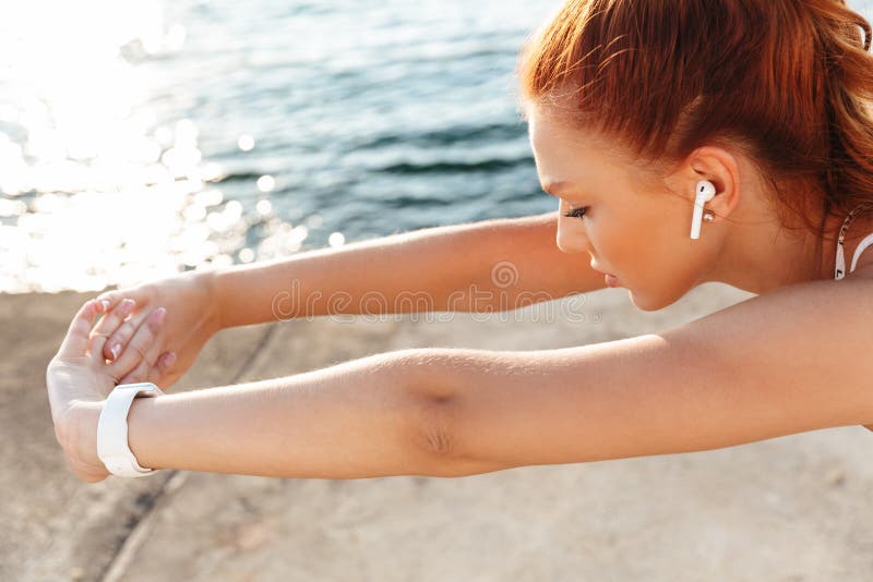 Belle jeune femme sportive rousse faire de l'exercice à l'extérieur à la plage le matin