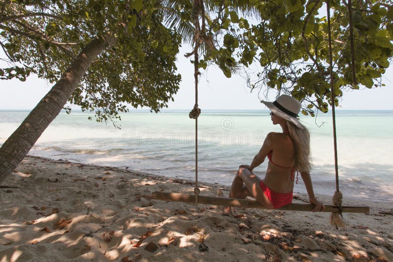 Belle jeune femme sur une oscillation se reposant sur la plage exotique santé lifestyle photo stock Belle jeune femme sur une oscillation se reposant sur la plage exotique santé lifestyle photo stock